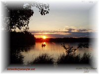 Two people fishing in a boat on a lake with the sun setting